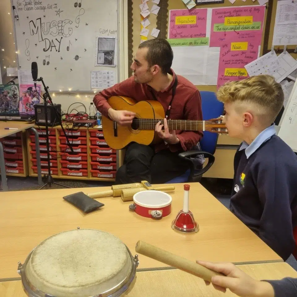 Henry teaching guitar and instruments in school